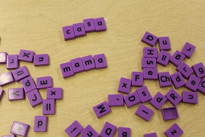 Purple letter tiles on a table spelling out the Spanish words "casa" and "mama"