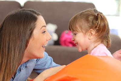 A parent and toddler face to face, laughing together during a Parent & Child Spanish class